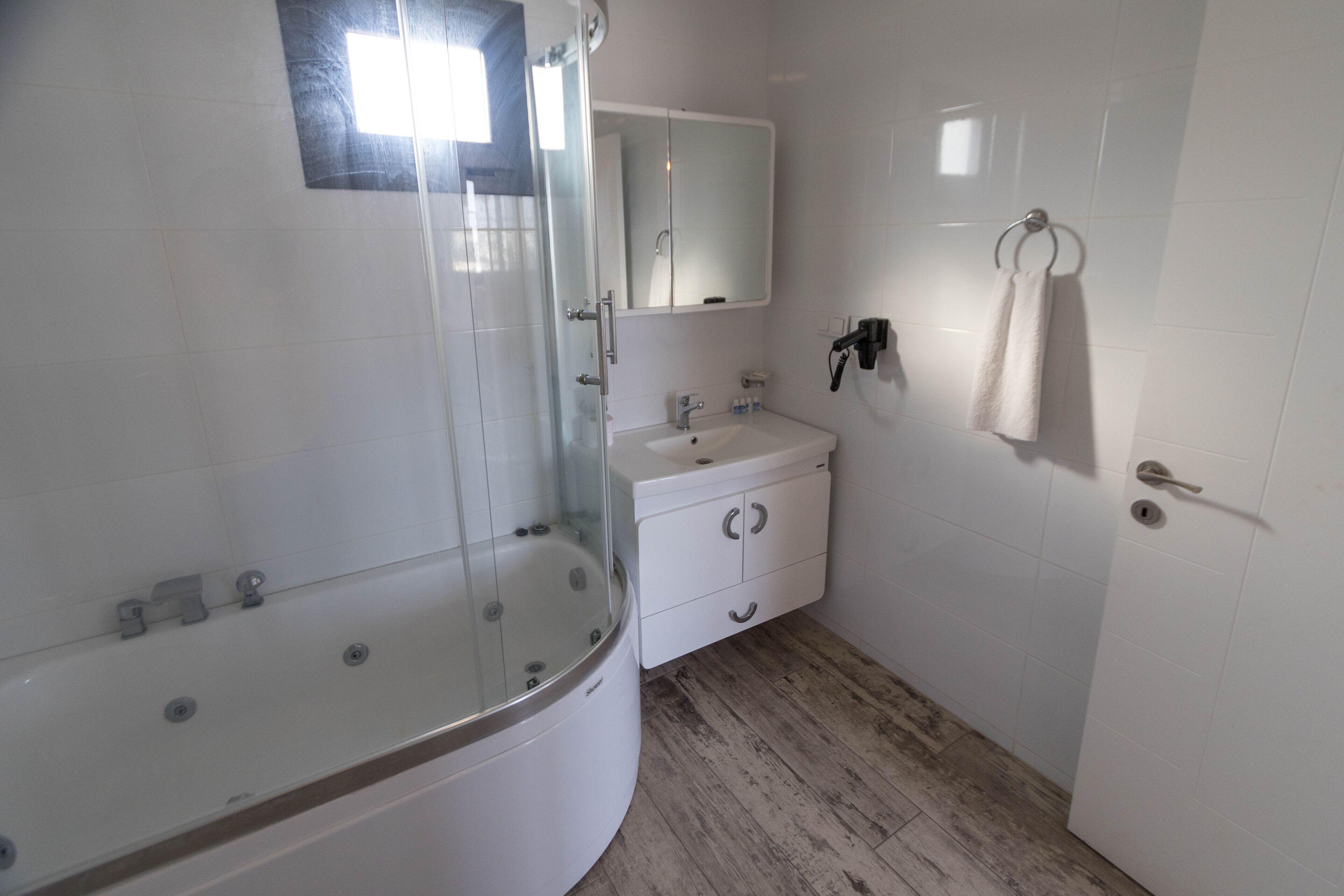 A bathroom with a glass-enclosed shower, a white sink, and a mirror above it.