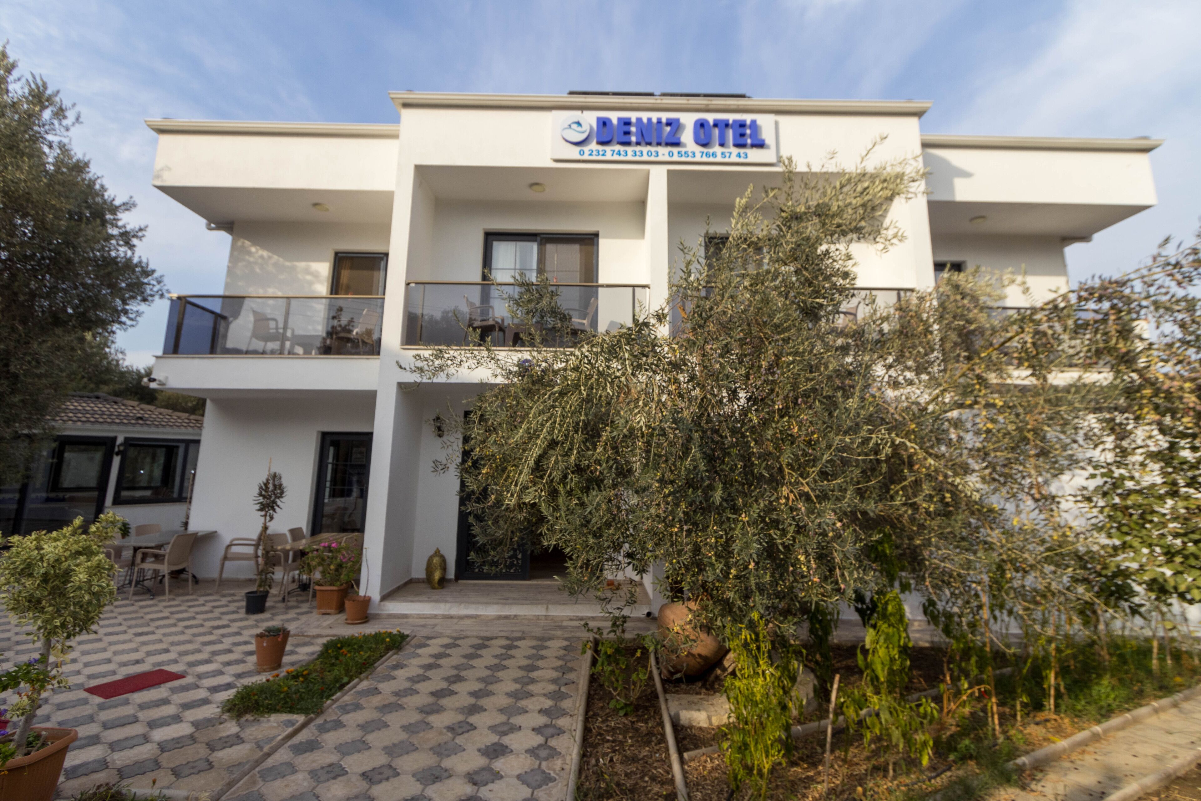 Un hotel moderno con tetto piano, un balcone con posti a sedere all'aperto e un giardino curato.
