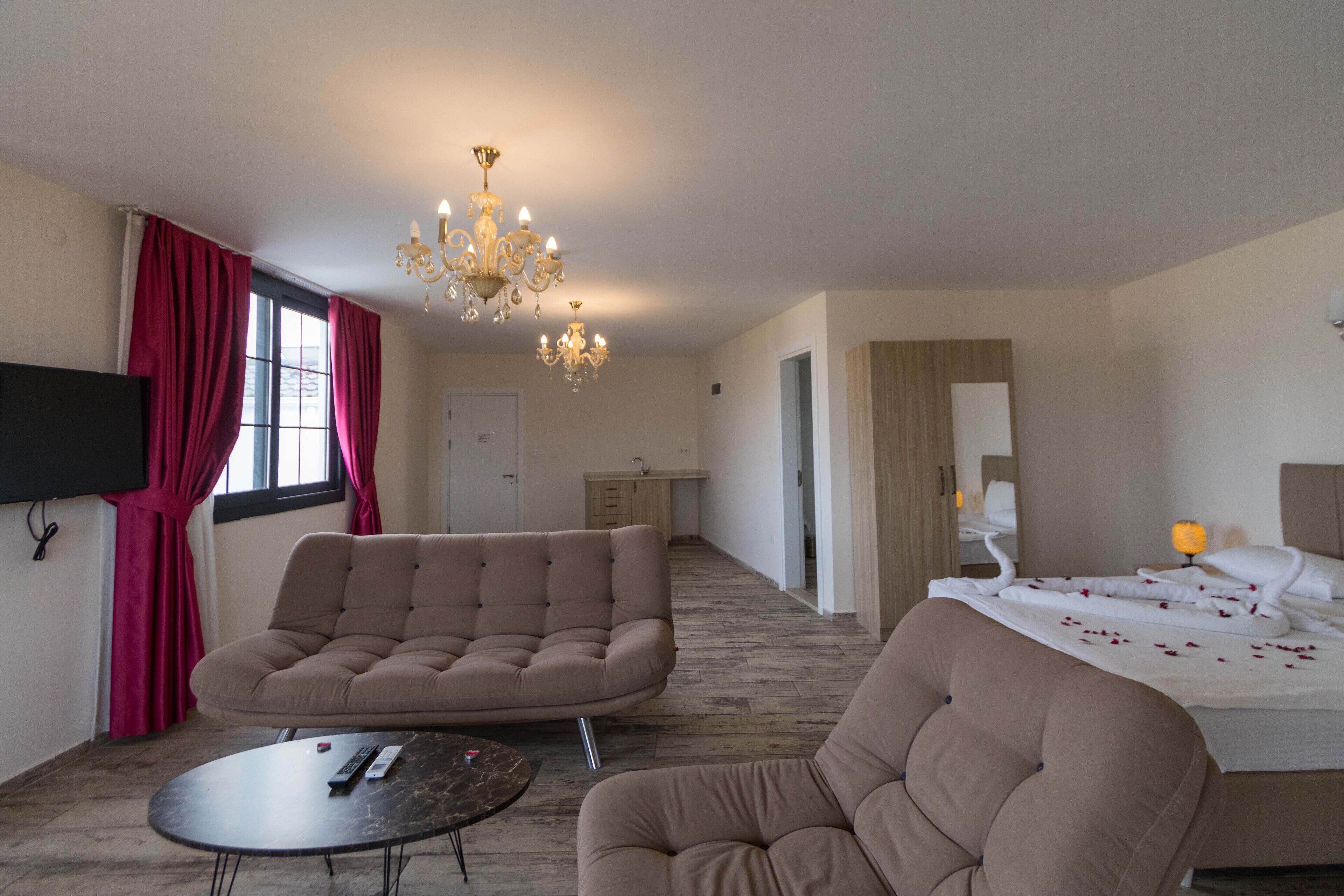 Een moderne hotelkamer met een bank, een bed, een televisie en een kroonluchter.