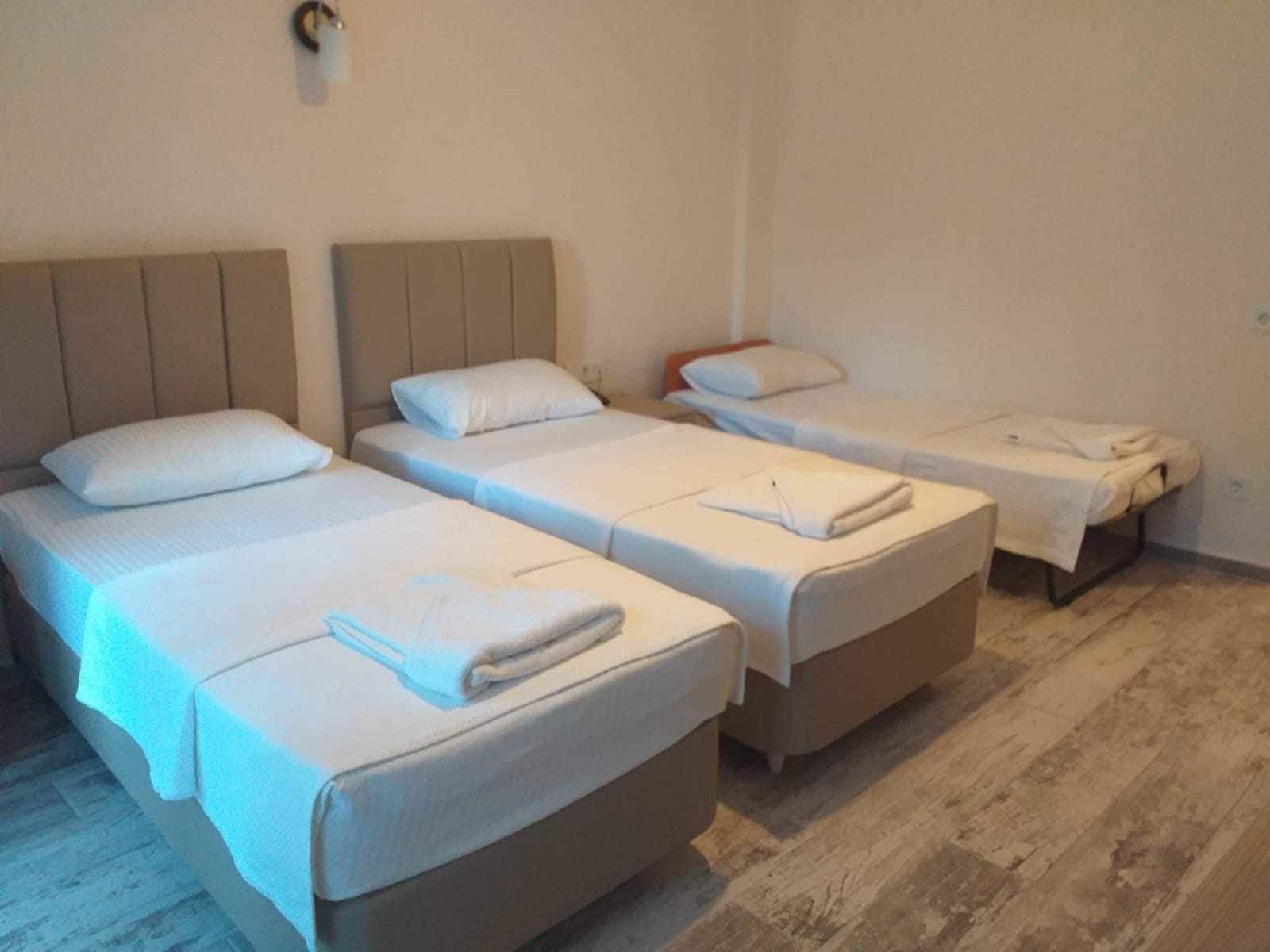 Una habitación con cuatro camas individuales, cada una con una almohada y una toalla doblada.