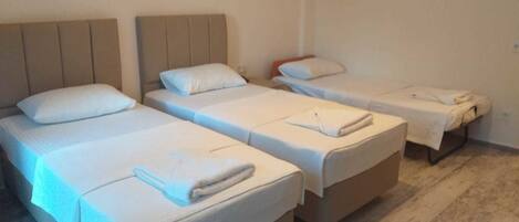 Una habitación con cuatro camas individuales, cada una con una almohada y una toalla doblada.