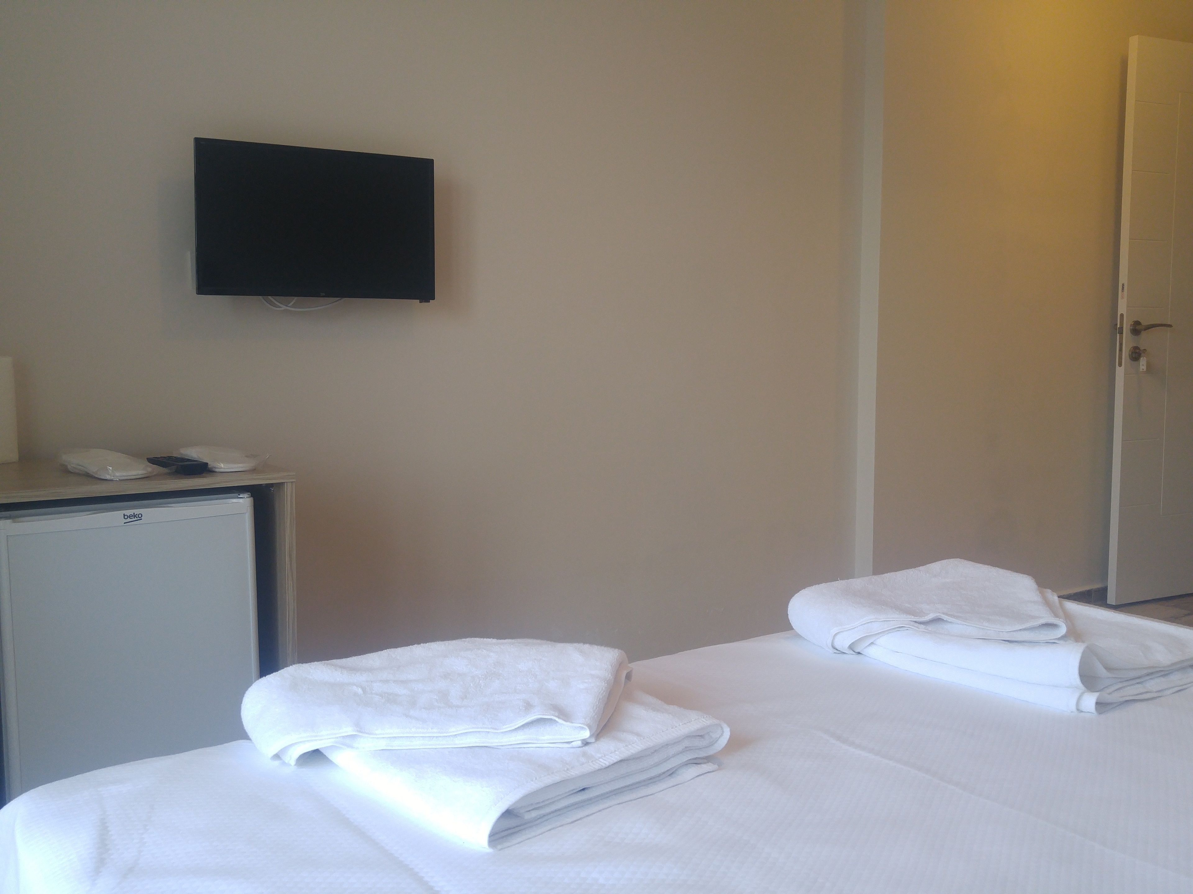 Habitación de hotel con cama, escritorio con teléfono y televisión en la pared.