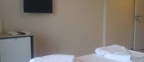 Habitación de hotel con cama, escritorio con teléfono y televisión en la pared.
