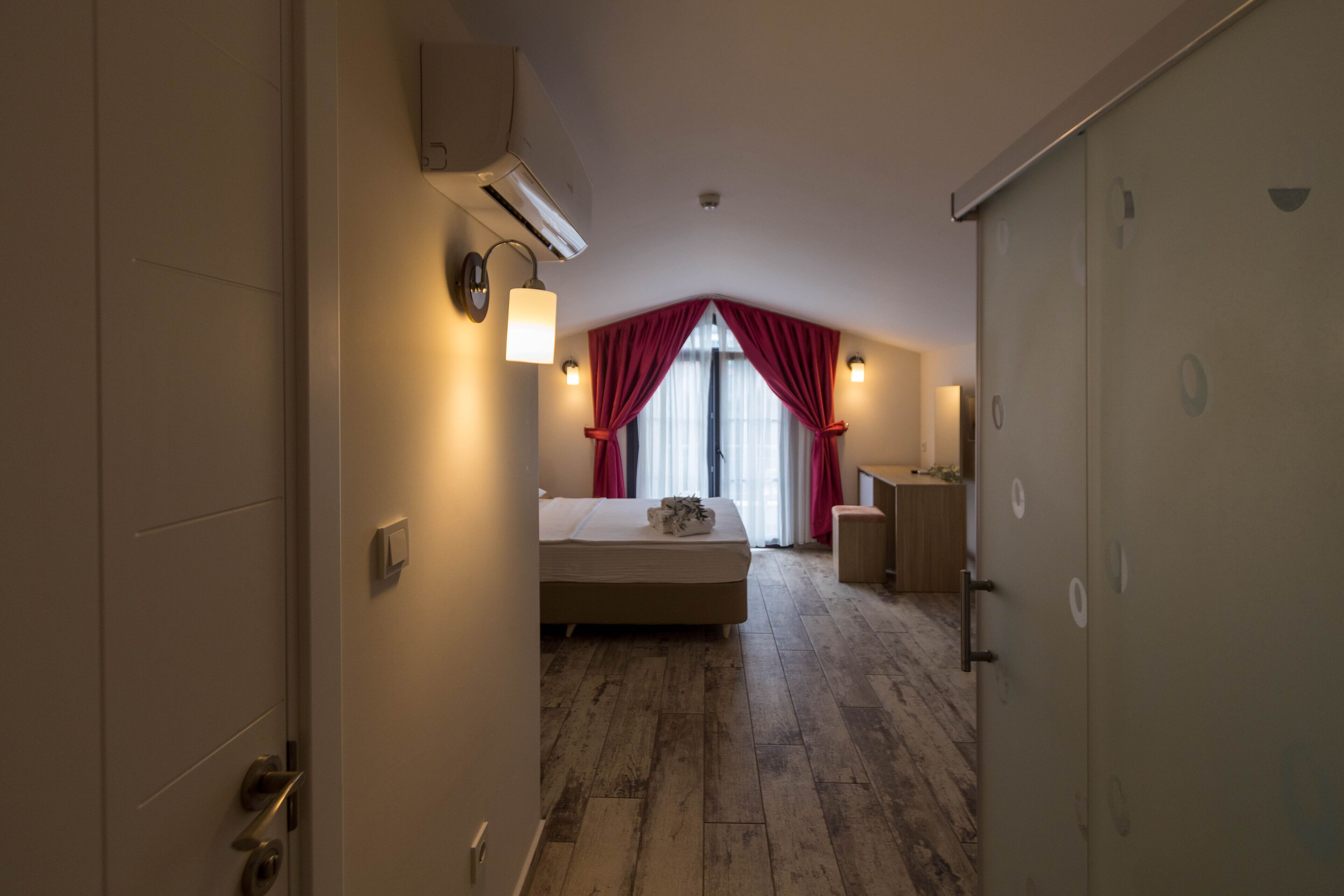 A hotel room with a bed, a desk, a chair, and a wardrobe.