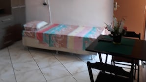 A room with a bed, a TV mounted on the wall, a desk with a chair, and a door. - Apartment in the city center (Praia dos Anjos)