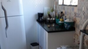A compact kitchen with a refrigerator, stove, and sink. - Apartment in the city center (Praia dos Anjos)