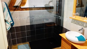 A bathroom with a shower, a sink, and a mirror.