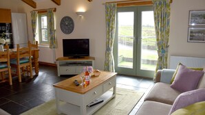 Una sala de estar con una mesa de centro de madera, televisor, sofá y un comedor con sillas y una mesa.