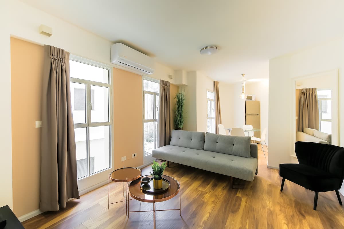 A modern living room with a sofa, a black chair, a round coffee table, and a potted plant.