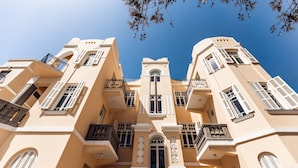 A multi-story building with balconies, arched windows, and a central tower. - House of Palm (Tel Aviv)