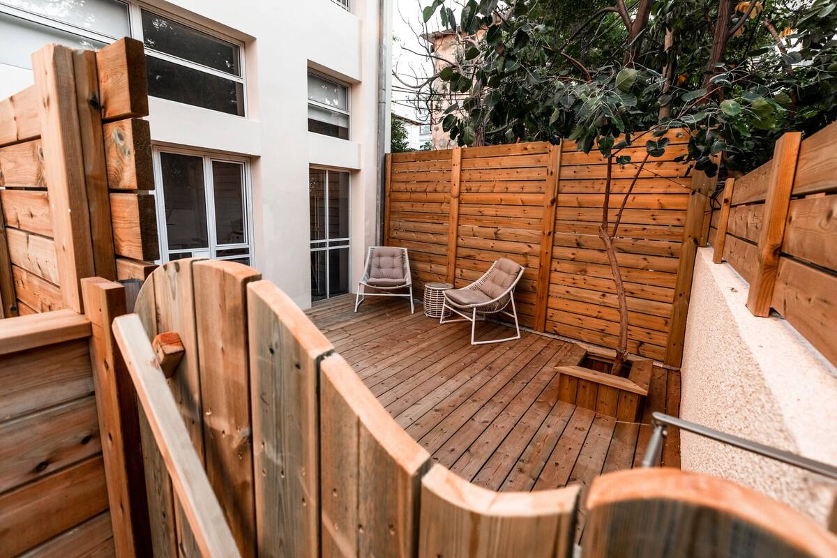 A wooden deck with two cushioned chairs and a small round table.