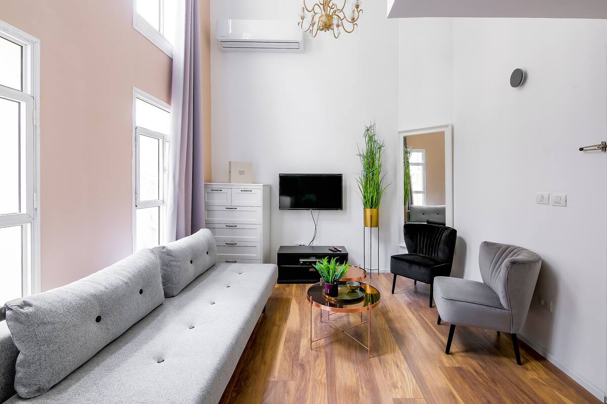 A modern living room with a sofa, a coffee table, a TV, and a chair.
