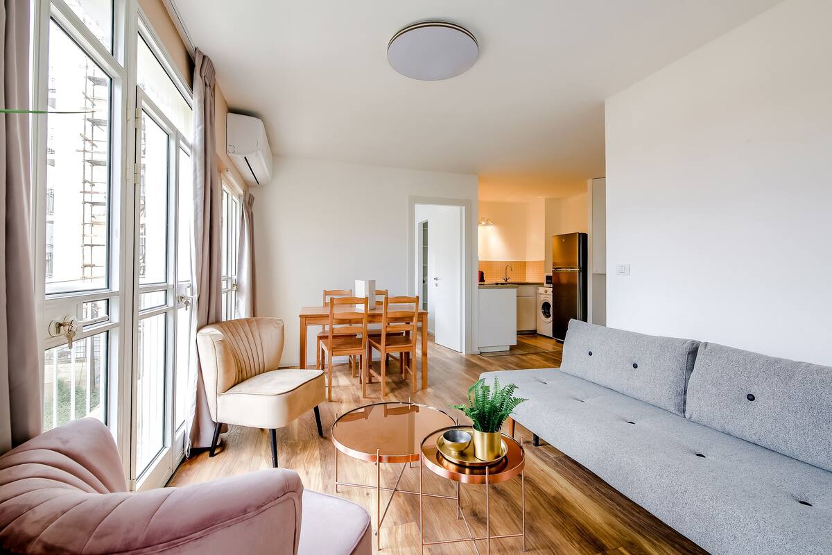 A modern living room with a sofa, a round coffee table, and a dining area with chairs and a table.