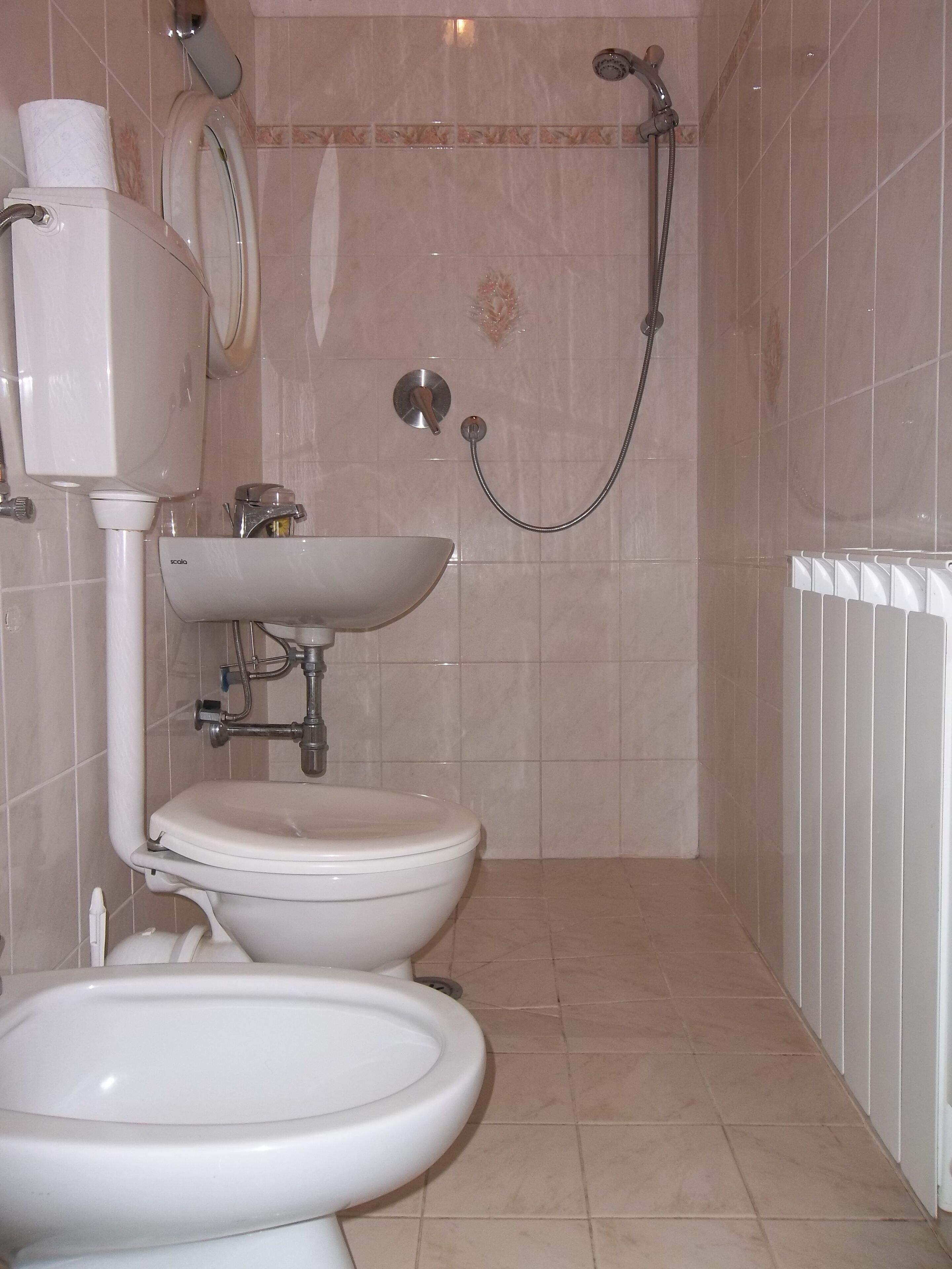 A bathroom with two toilets, a sink, a shower, and a toilet paper holder.