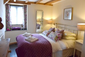 A bedroom with a large bed, a window with floral curtains, a mirror, and bedside lamps. - Rural Complex 7 Lux Cottages, Oak Cottage, Upside Down Acc, Beautiful View (Tregony)