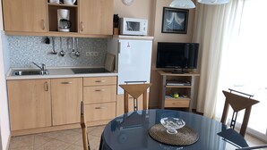 A compact kitchen with a microwave, coffee maker, and a TV on a stand.