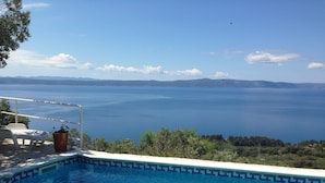 A swimming pool with a view of the sea and distant mountains.