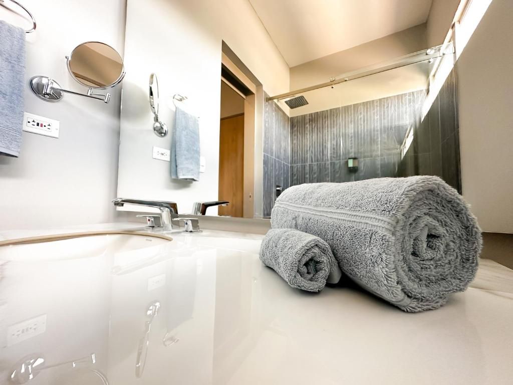 A modern bathroom with a large mirror, a sink, and a towel.