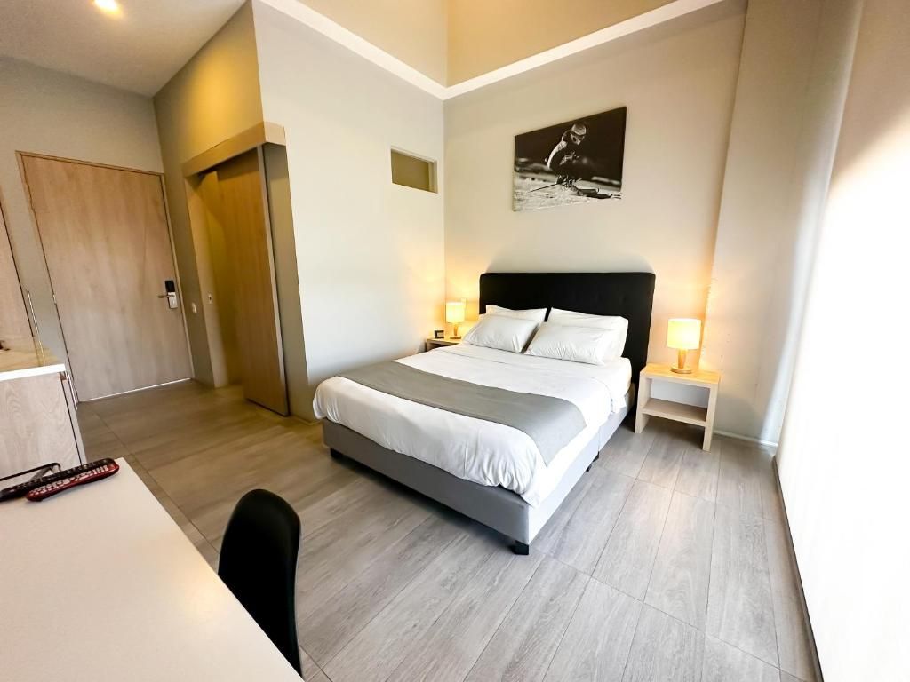 A hotel room with a bed, bedside tables, a desk, and a chair.