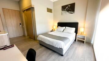 A hotel room with a bed, bedside tables, a desk, and a chair.