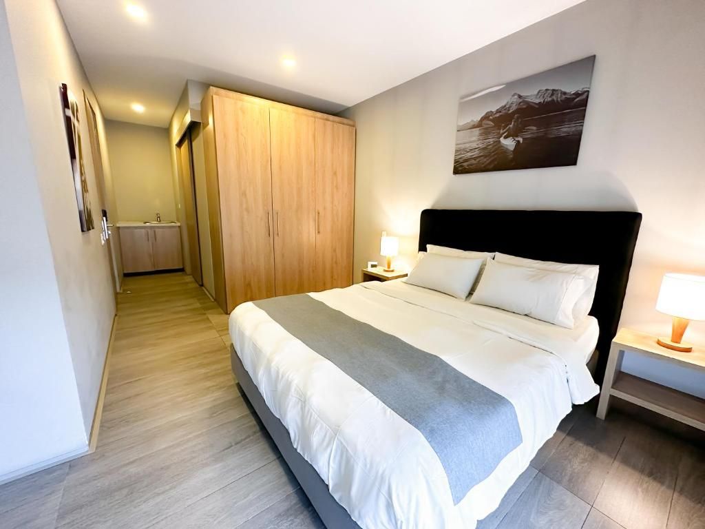 Habitació d'hotel amb llit, una tauleta de nit, un quadre penjat a la paret i un armari de fusta.