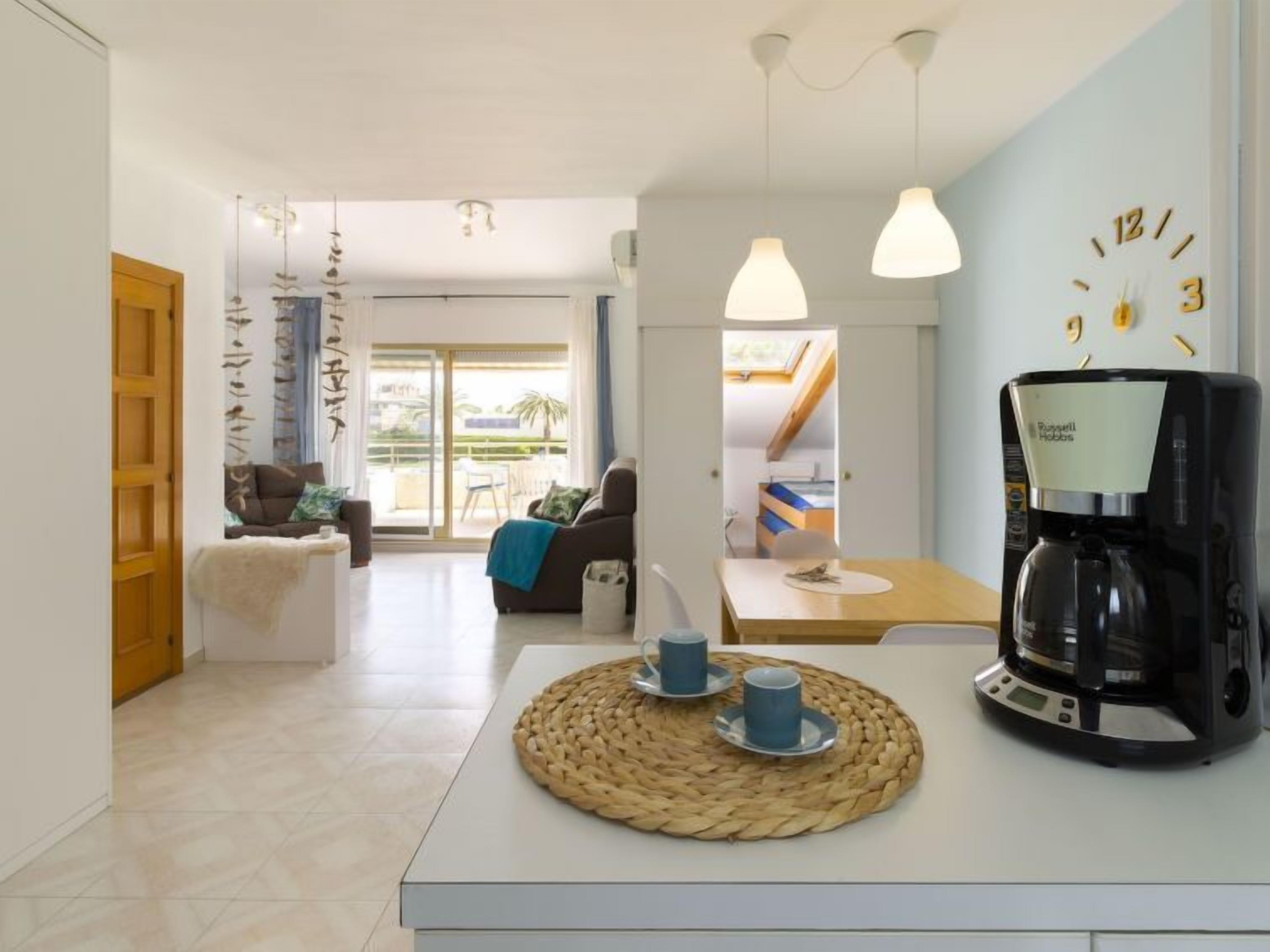 Una sala de estar moderna con un sofá, una mesa de centro con tazas y una cafetera.