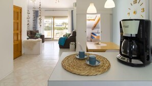 Una sala de estar moderna con un sofá, una mesa de centro con tazas y una cafetera.