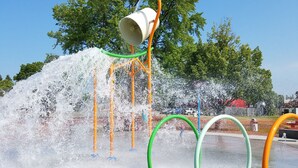 Un área de juegos con agua que incluye múltiples chorros y un cubo grande.