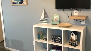 Una habitación con un mueble blanco de entretenimiento, un televisor montado en la pared y un estante también fijado a la pared.