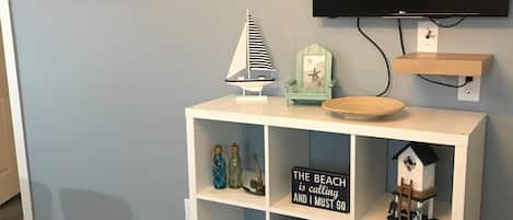A room with a white entertainment unit, a mounted TV, and a wall-mounted shelf.