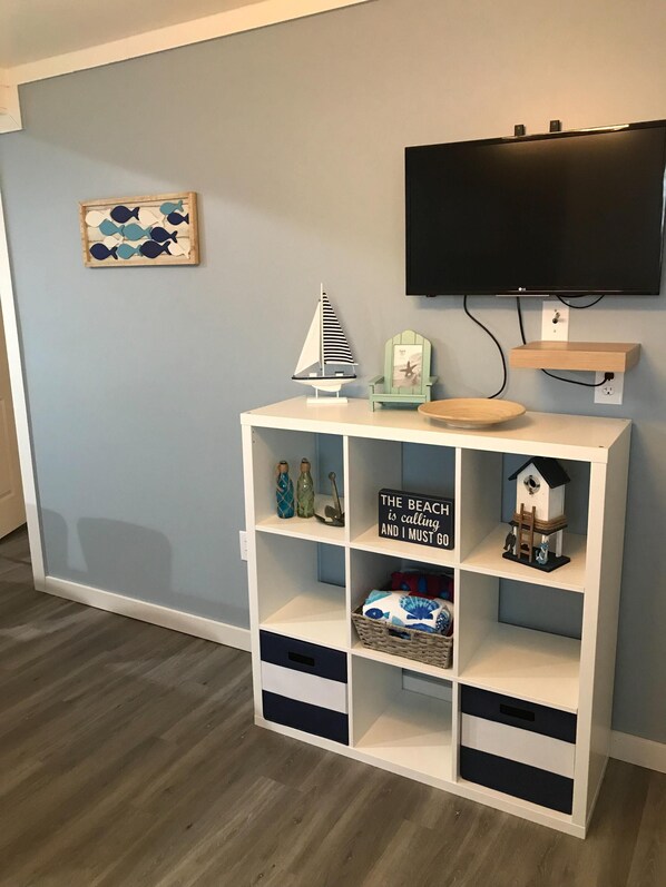 A room with a white entertainment unit, a mounted TV, and a wall-mounted shelf.