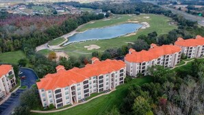 Un hotel de varios pisos con tejados de tejas rojas, un campo de golf y un lago grande.