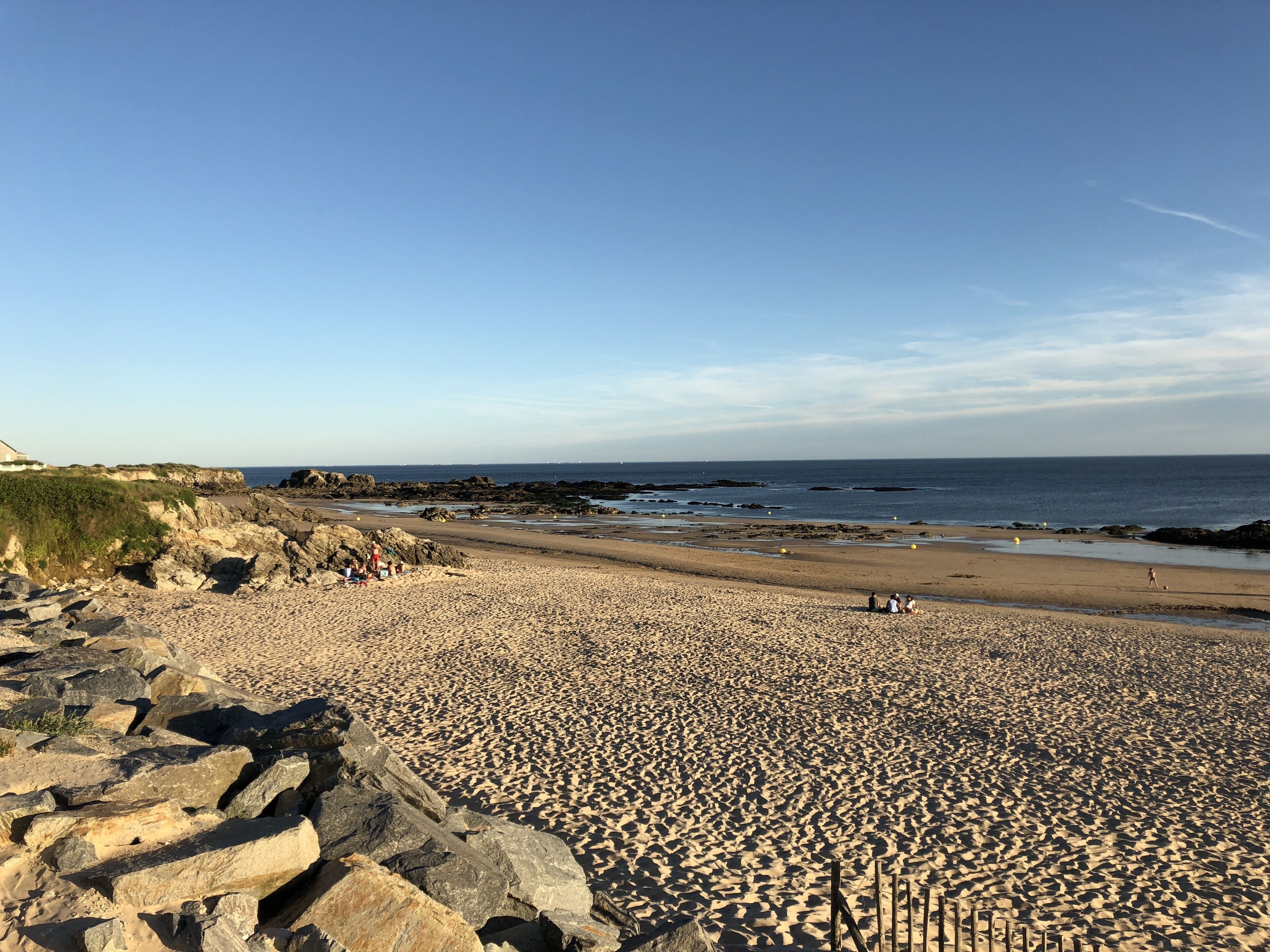 Una playa con terreno rocoso y una vista despejada del mar.