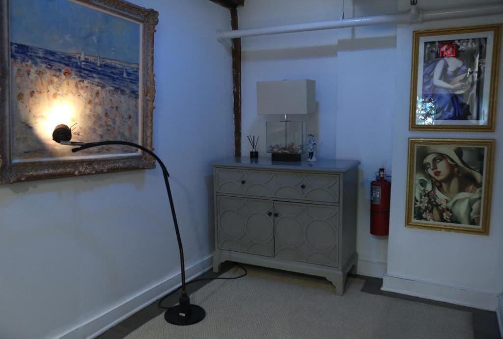 A room with a painting, a lamp, a cabinet, and a fire extinguisher.