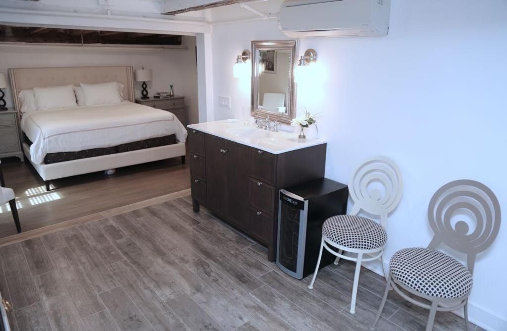 Quarto com cama, penteadeira com espelho, pequena escrivaninha e duas cadeiras.