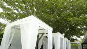 A covered outdoor seating area with white canopies and brown furniture. - Harpoon House (Southampton)
