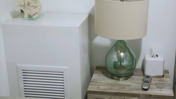 A bedside table with a green glass lamp, a tissue box, and a remote control.