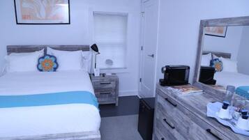 Habitación de hotel con cama, mesita de noche, cómoda y espejo.