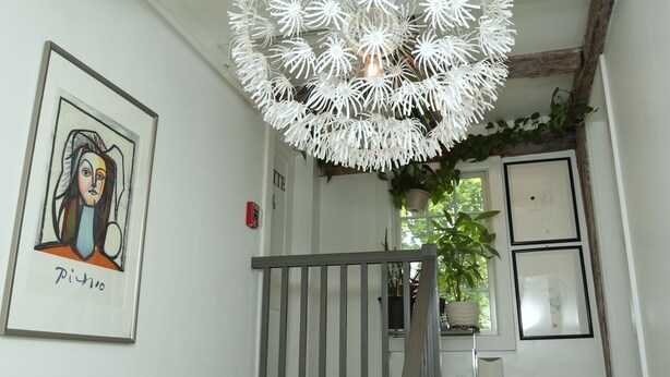 A staircase with a white railing, a white chandelier, and framed artwork on the walls. - Harpoon House (Southampton)