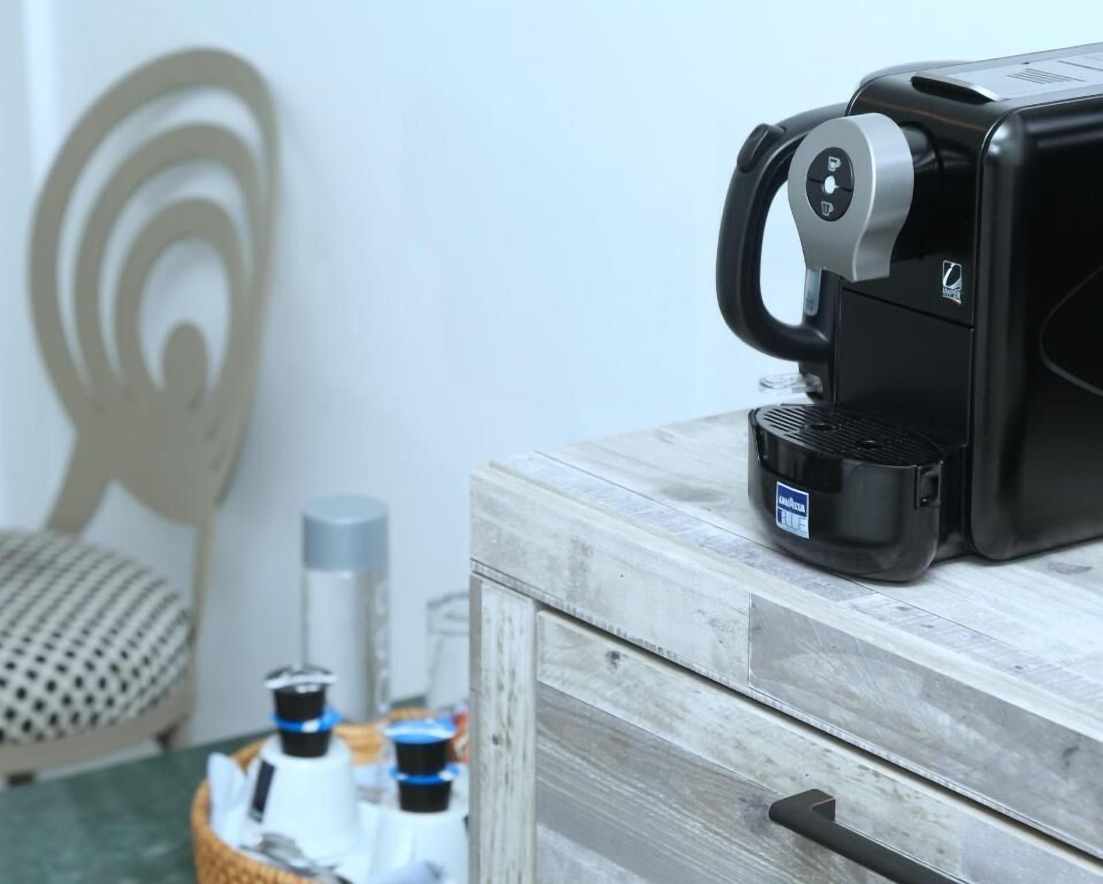 Een koffieapparaat op een houten kastje met een hendel, een mand met flessen en een muur met een rond ontwerp.