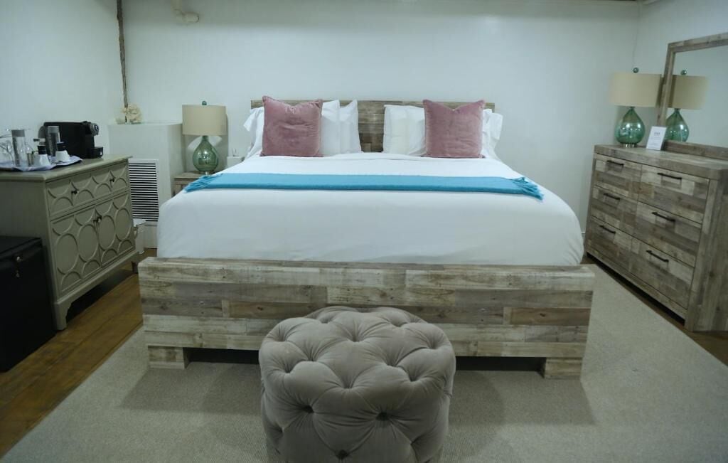 A bedroom with a bed, bedside tables, a dresser, and a small ottoman.