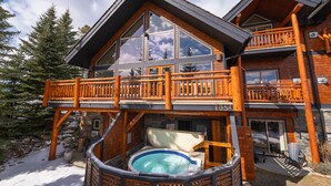 Une cabane en rondins dotée d’un bain à remous, de balcons en bois et de fondations en pierre.