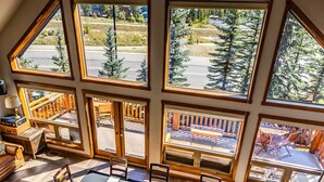 Un espace repas avec une grande table dressée pour six personnes, entouré de grandes fenêtres offrant une vue sur les montagnes.