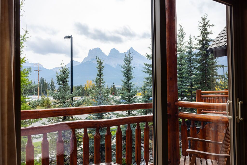 Un balcon en bois offrant une vue sur les montagnes et les arbres.