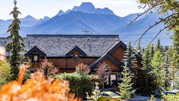 A brick building with a sloped roof, a wooden porch, and a mountain backdrop.