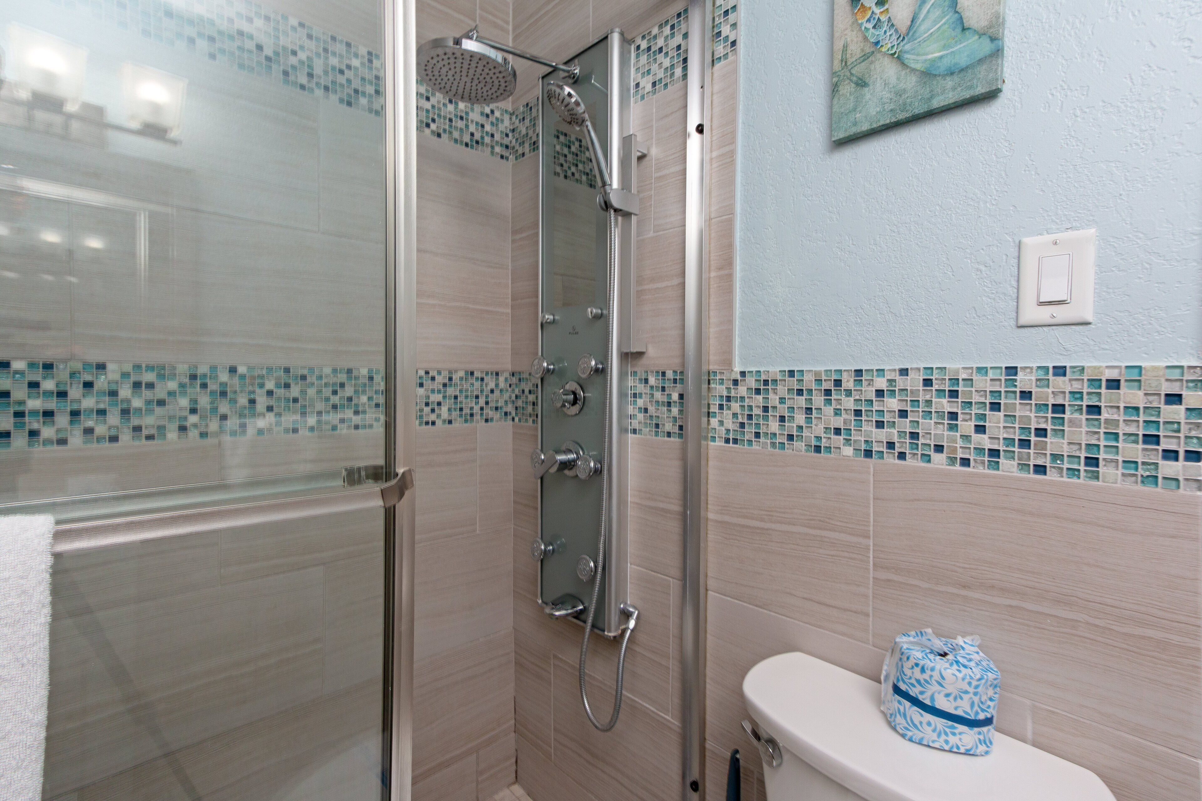 A bathroom with a glass-enclosed shower, a toilet, and a sink.