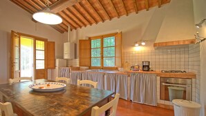 A kitchen with a wooden table, chairs, a stove, a sink, and a window with curtains. - Beautiful private villa with WIFI, private pool, TV, terrace, pets allowed and panoramic view (Legoli)