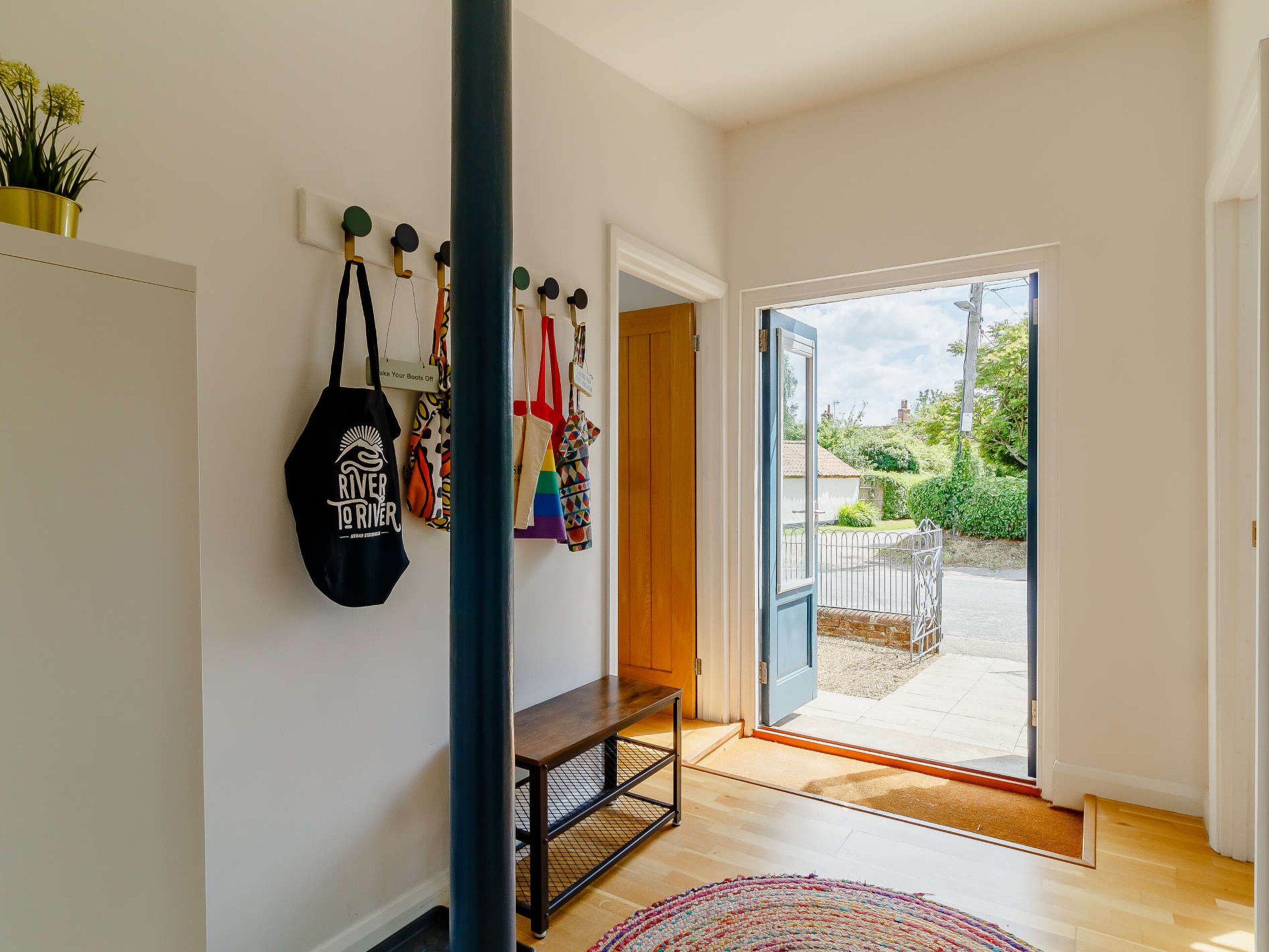 Ein modernes Interieur mit einer Bank, einem an der Wand befestigten Gepäckträger und einer Tür, die zu einem Außenbereich führt.