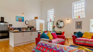 A modern kitchen with white cabinets, a black stove, and a dining area with colorful furniture. - 4 bedroom accommodation in Hindolveston, near Holt (Hindolveston, near Holt)