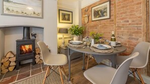 Una habitación acogedora con chimenea, una mesa de comedor para dos personas y una pared de ladrillo.